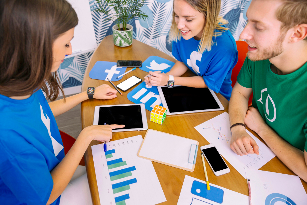 group-of-people-looking-at-digital-tablet-with-social-media-icons-at-workplace